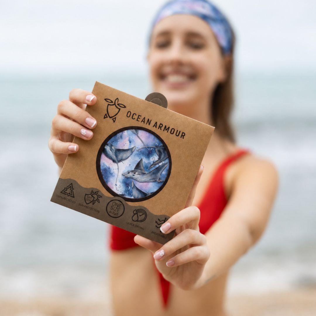 Person holding an 'Ocean Armour' product packaging on a beach